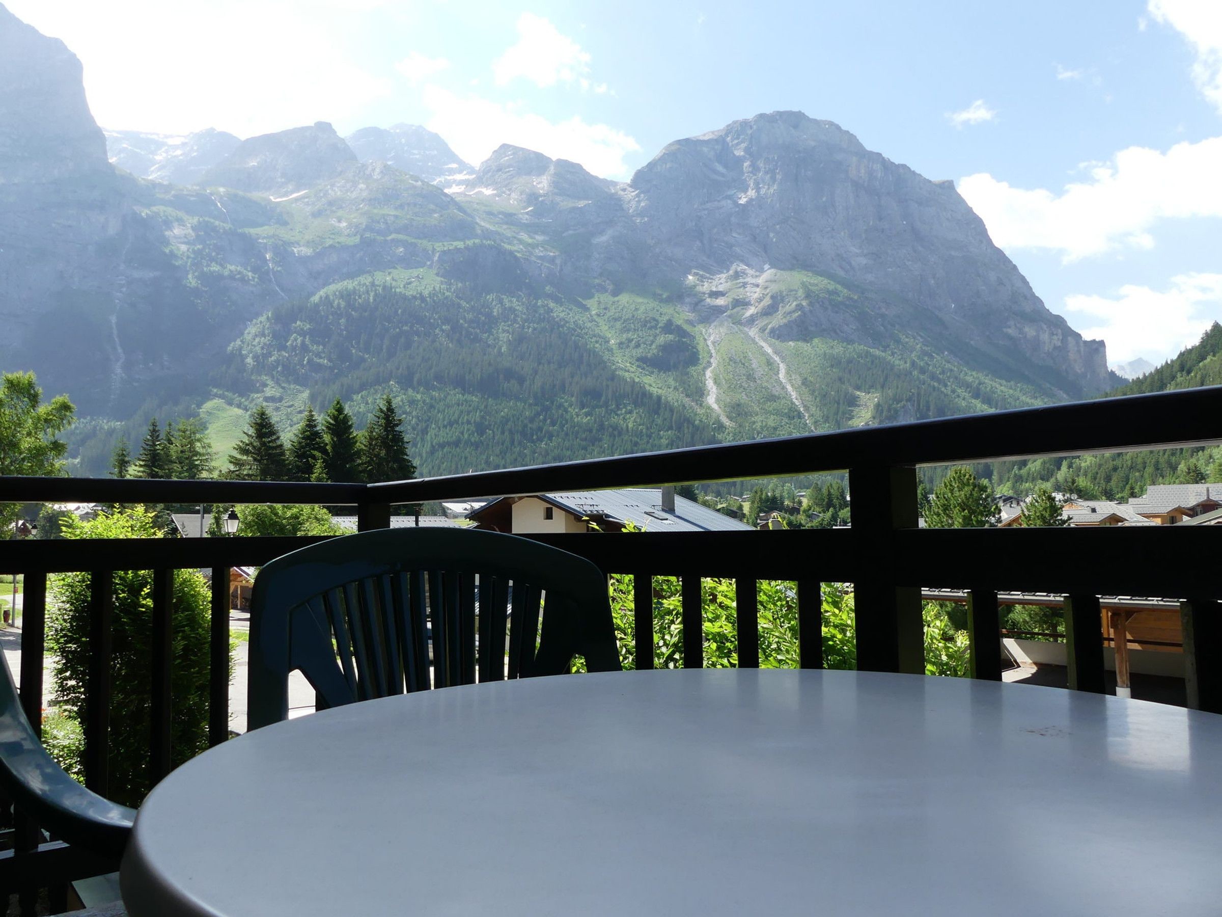 Un balcon avec une table et des chaises donnant sur un paysage montagneux.