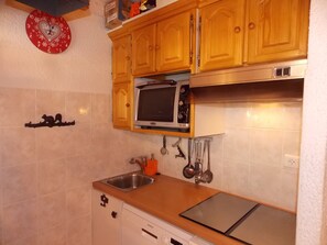 A kitchen with wooden cabinets, a microwave, a sink, and a dishwasher. - Chalet in city center - 8 guests (Pralognan-la-Vanoise)