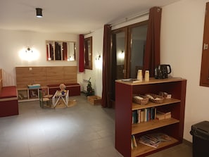 A living room with a sofa, a small table with a globe, a bookshelf, and a sliding glass door. - Grand T4 ski aux pieds | À 100m du centre | Balcon (Villarodin-Bourget)
