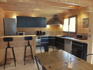 Eine moderne Küche mit Holzschnitzereien, einer zentralen Kochinsel mit Barhocker und einem Esstisch.