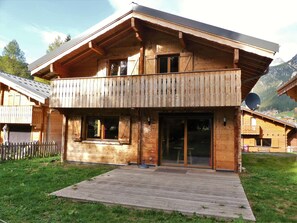 A wooden chalet with a balcony, large windows, and a wooden deck. - Spacious chalet with terrace - 10 guests (Pralognan-la-Vanoise)