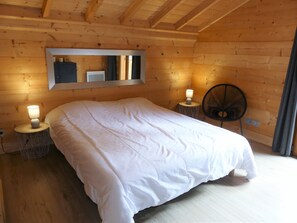 Een kamer met houten lambrisering, een bed, twee bedlampen, een ronde tafel en een stoel.