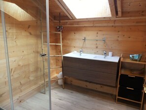 A wooden cabin bathroom with a skylight, a white sink, a mirror, and a wooden shelf. - Spacious chalet with terrace - 10 guests (Pralognan-la-Vanoise)