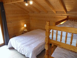 A wooden cabin room with a bed, a nightstand, and a lamp. - Spacious chalet with terrace - 10 guests (Pralognan-la-Vanoise)