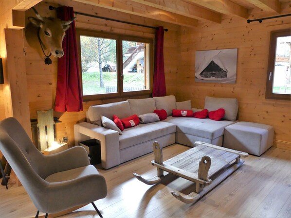 A cozy room with a sectional sofa, a wooden rocking chair, and a wooden sled. - Spacious chalet with terrace - 10 guests (Pralognan-la-Vanoise)
