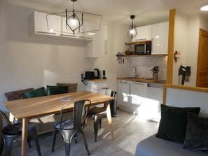Eine kleine Küche mit Essbereich, inklusive Holztisch, Stühle und einer Couch.