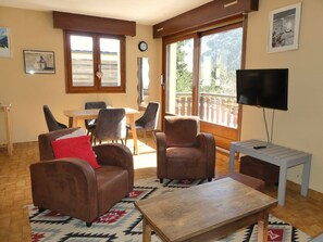 A living room with a sofa, armchairs, a coffee table, a TV, and a balcony with a view. - Charming apartment - 5 guests (Pralognan-la-Vanoise)