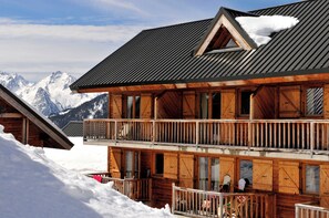 A wooden chalet with a balcony, set against a snowy mountain backdrop. - Ski aux pieds | Proche du télésiège | Piscine (Saint-François-Longchamp)