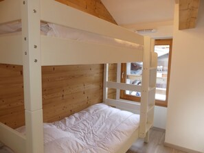 A bunk bed with a wooden headboard and a window with a view of a balcony. - Bright apartment with parking - 4 guests (Pralognan-la-Vanoise)