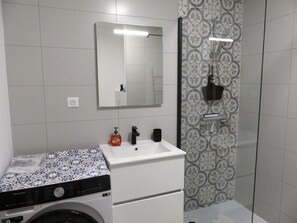 A modern bathroom with a washing machine, a sink, and a shower area. - Bright apartment with parking - 4 guests (Pralognan-la-Vanoise)