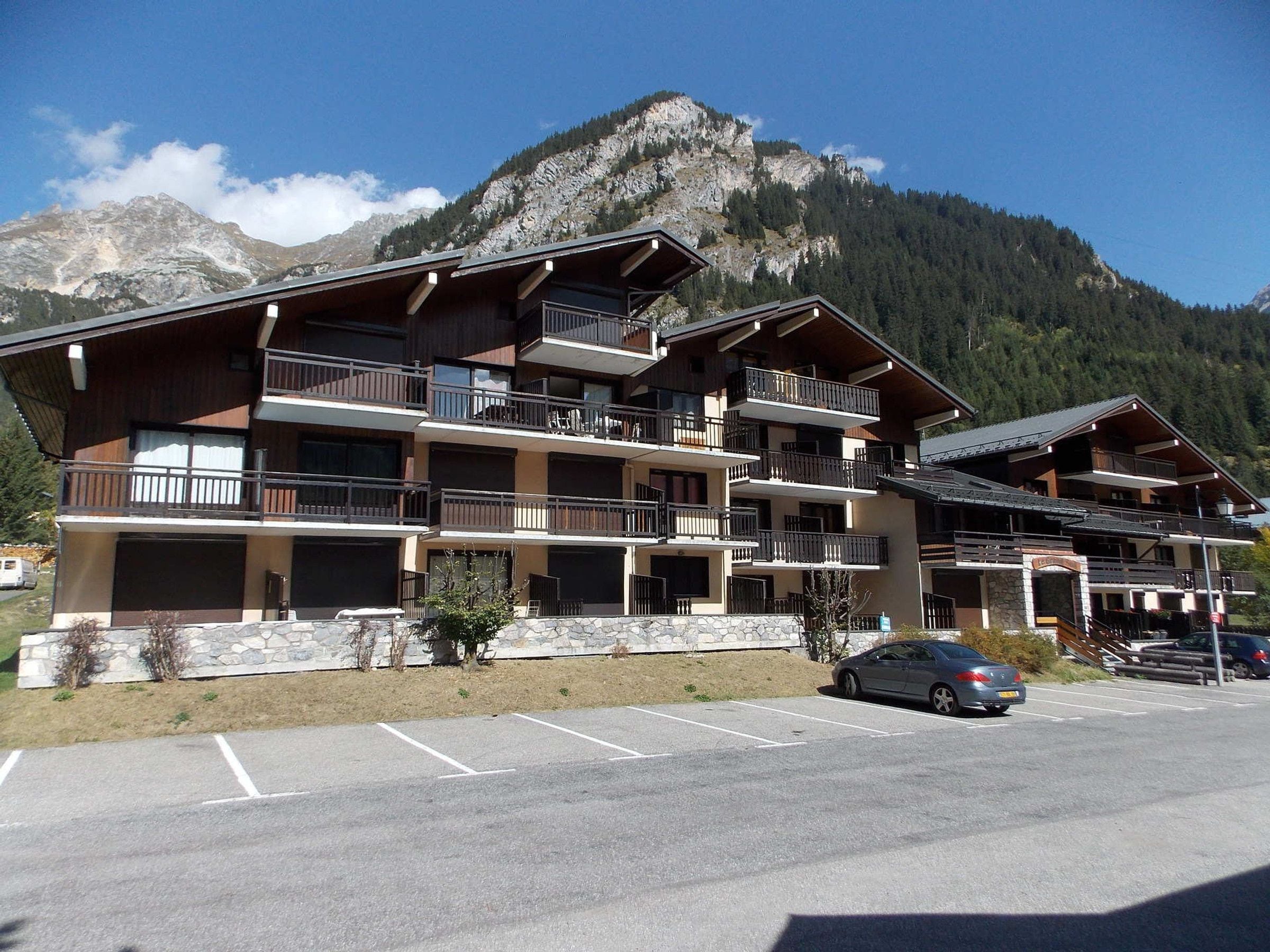Un hôtel à plusieurs étages doté de balcons, d’un parking et situé dans un cadre montagneux.
