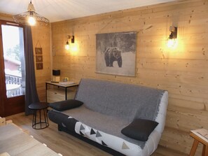 Ein gemütliches Blockhaus-Interieur mit einer Couch, einem Tisch und einem Bärenbild an der Wand.