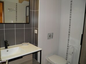 Ein Badezimmer mit Waschbecken, Spiegel, Toilette und Dusche.