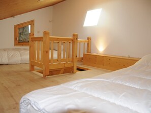 Ein Schlafzimmer mit einem Holzbettgestell, einem Einzelbett, einem Bild an der Wand und einem Fenster.