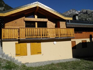 Ein zweistöckiges Gebäude mit Balkon, Holzläden und Bergblick.