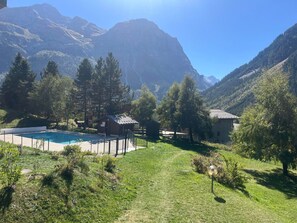 A pool area with a mountain backdrop, surrounded by trees and a small building. - Apartment with wifi, pets welcome - 5 guests (Pralognan-la-Vanoise)