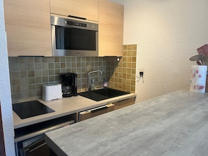 Een moderne keuken met een ingebouwde magnetron, een koffiezetapparaat en een spoelbak.