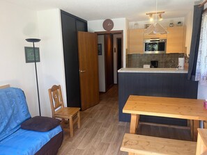A compact living space with a kitchenette, a dining area, and a seating area with a sofa and a chair. - Apartment with wifi, pets welcome - 5 guests (Pralognan-la-Vanoise)