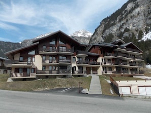 Un hotel de varios pisos con balcones, con montañas al fondo.