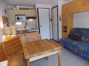 Un espacio habitable pequeño con kitchenette, una mesa de comedor y un sofá.