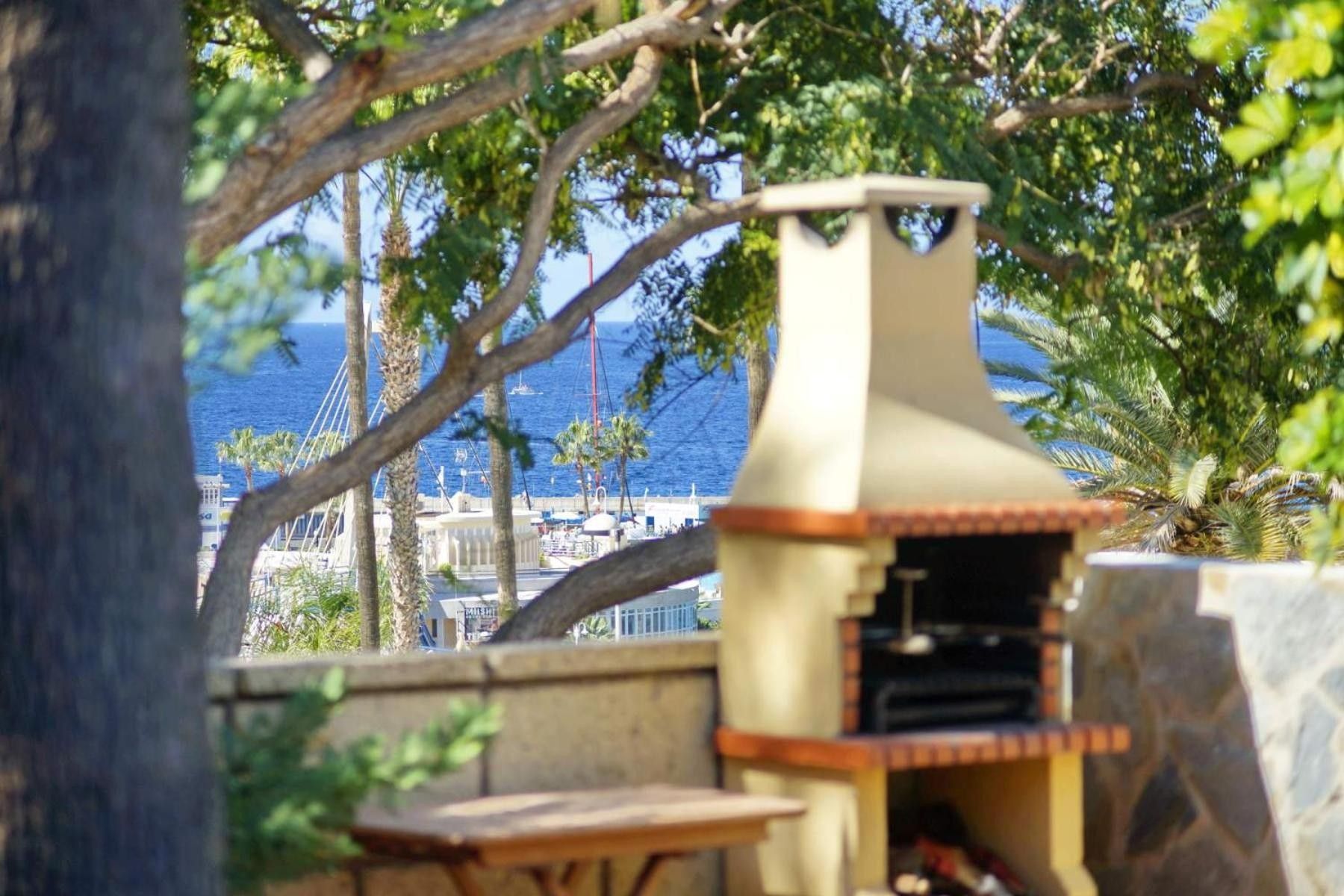 A barbecue grill with a view of the sea and buildings in the background.