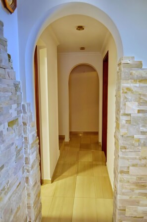 A hallway with a tiled floor, an arched doorway, and a stone wall on one side. - Vacation Home 'Natali' with Sea View, Wi-Fi and Air Conditioning (Costa Adeje)