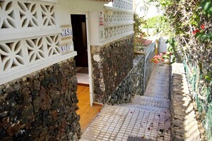A narrow stone pathway leading to a doorway with a sign that reads 'CASA NATAL.'