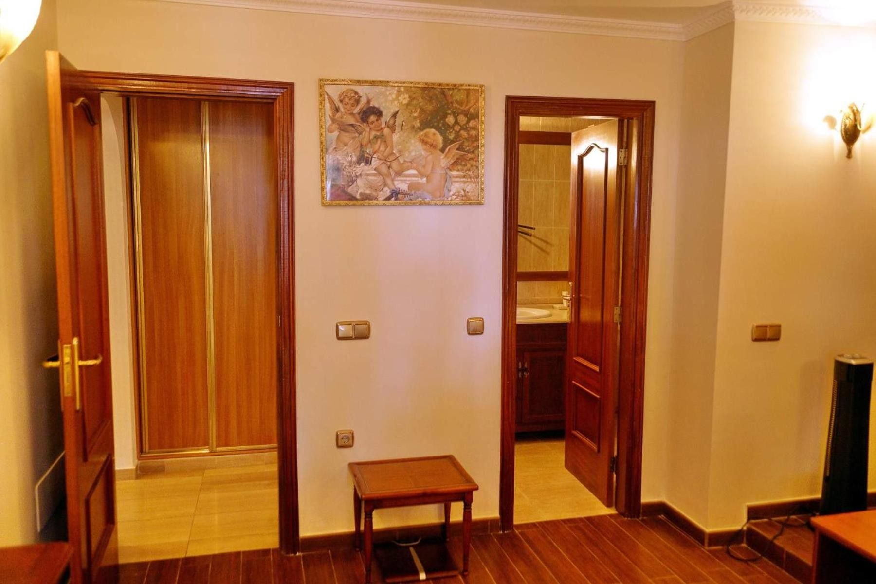 A hallway with wooden doors, a small table, and a painting on the wall.