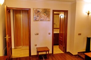 A hallway with wooden doors, a small table, and a painting on the wall.