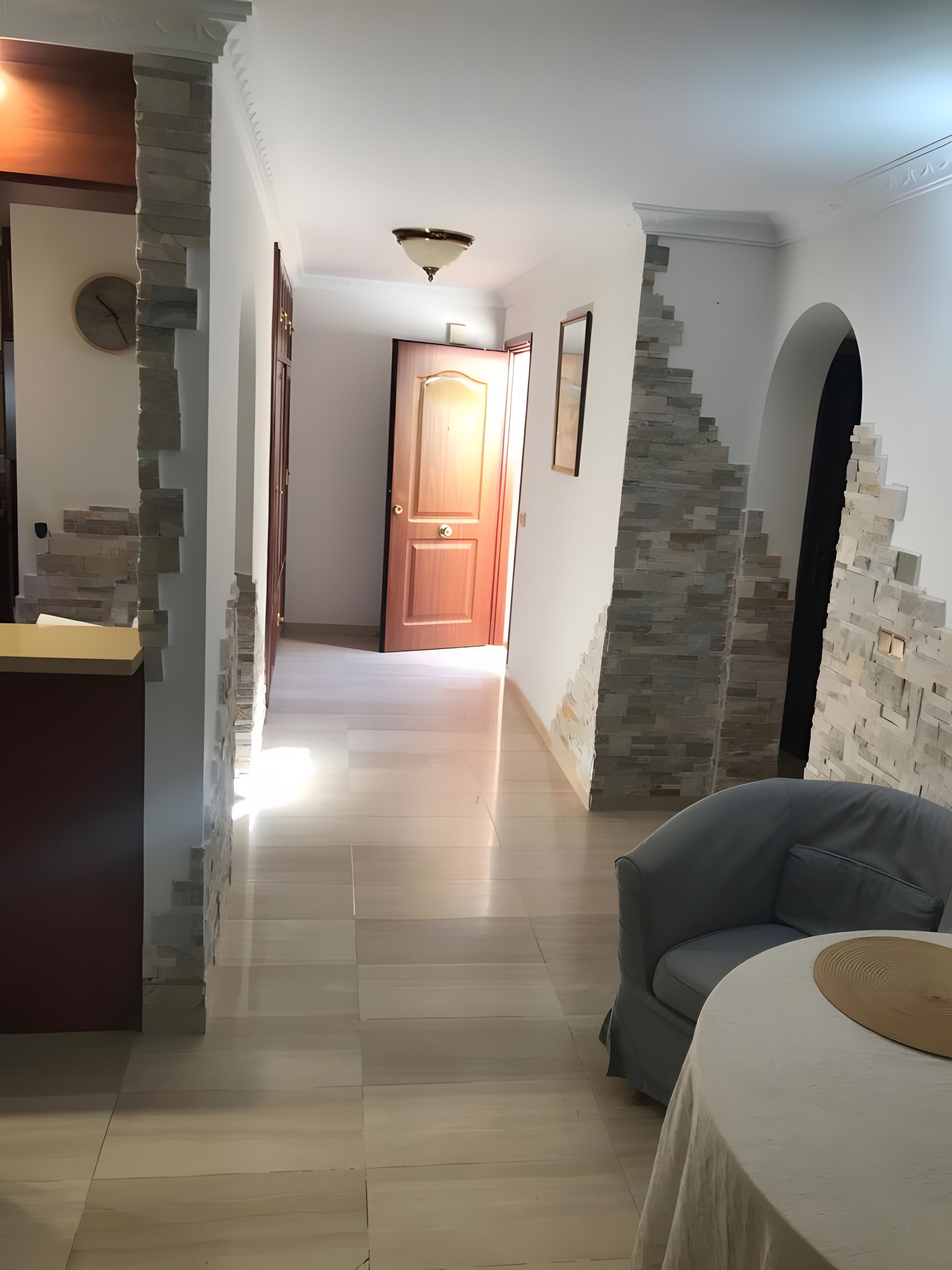 A hallway with a wooden door, stone walls, and a staircase.