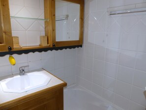Ein Badezimmer mit einem weißen Waschbecken, einem Holz-Waschtisch und einem Spiegel mit Holzrahmen.