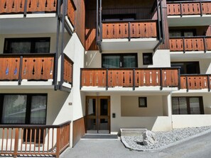A multi-story building with balconies, a door, and a small garden area. - Apartment near slopes - 4 guests (Pralognan-la-Vanoise)