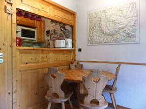 A wooden kitchen with a microwave, toaster, and various utensils. There is a dining table with wooden chairs. - Apartment near slopes - 4 guests (Pralognan-la-Vanoise)