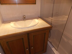 A bathroom with a white sink, wooden cabinets, and a glass shower enclosure. - 3-star duplex - 4 guests (Pralognan-la-Vanoise)