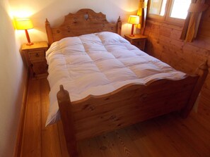 Ein hölzernes Bett mit einer Steppdecke in einem Zimmer mit Holzböden und zwei Nachttischlampen.