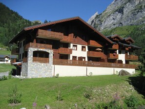 A multi-story chalet with balconies, set against a mountainous backdrop. - 3-star duplex - 4 guests (Pralognan-la-Vanoise)