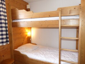 A bunk bed with a wooden ladder and a single bed below. - Convenient apartment - 6 guests (Pralognan-la-Vanoise)