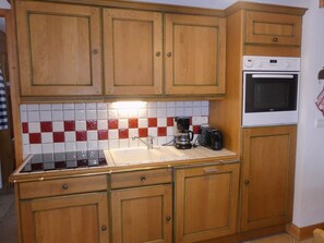 A kitchen with wooden cabinets, a tiled backsplash, a sink, a stove, and a microwave. - Convenient apartment - 6 guests (Pralognan-la-Vanoise)