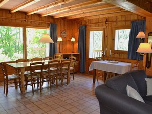 Un interior de madera con comedor, sofá y una mesa con mantel blanco.