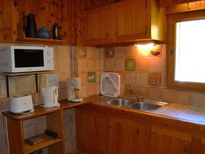 A kitchen with wooden cabinets, a microwave, a coffee maker, and a sink. - Family chalet with parking - 14 guests (Pralognan-la-Vanoise)