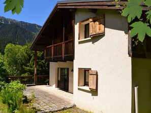 A two-story building with a balcony, a wooden door, and a window with a shutter.