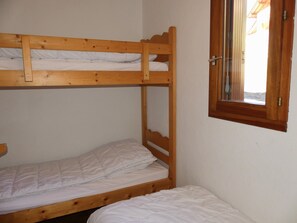A bunk bed with a wooden frame and white bedding, a small window with a wooden frame, and a door with a brass handle. - Apartment in Pralognan-la-Vanoise - 5 guests (Pralognan-la-Vanoise)