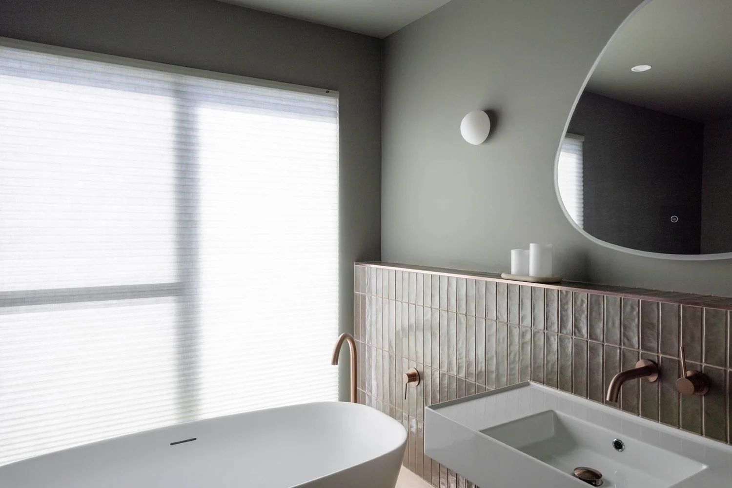 A modern bathroom with a freestanding bathtub, a vanity with a sink, and a large mirror.