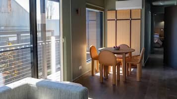 A modern interior with a dining area, a sofa, and a view through a sliding door.