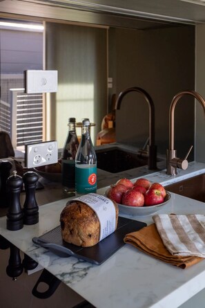 A kitchen counter with a loaf of bread, a bottle of water, and a bowl of apples.