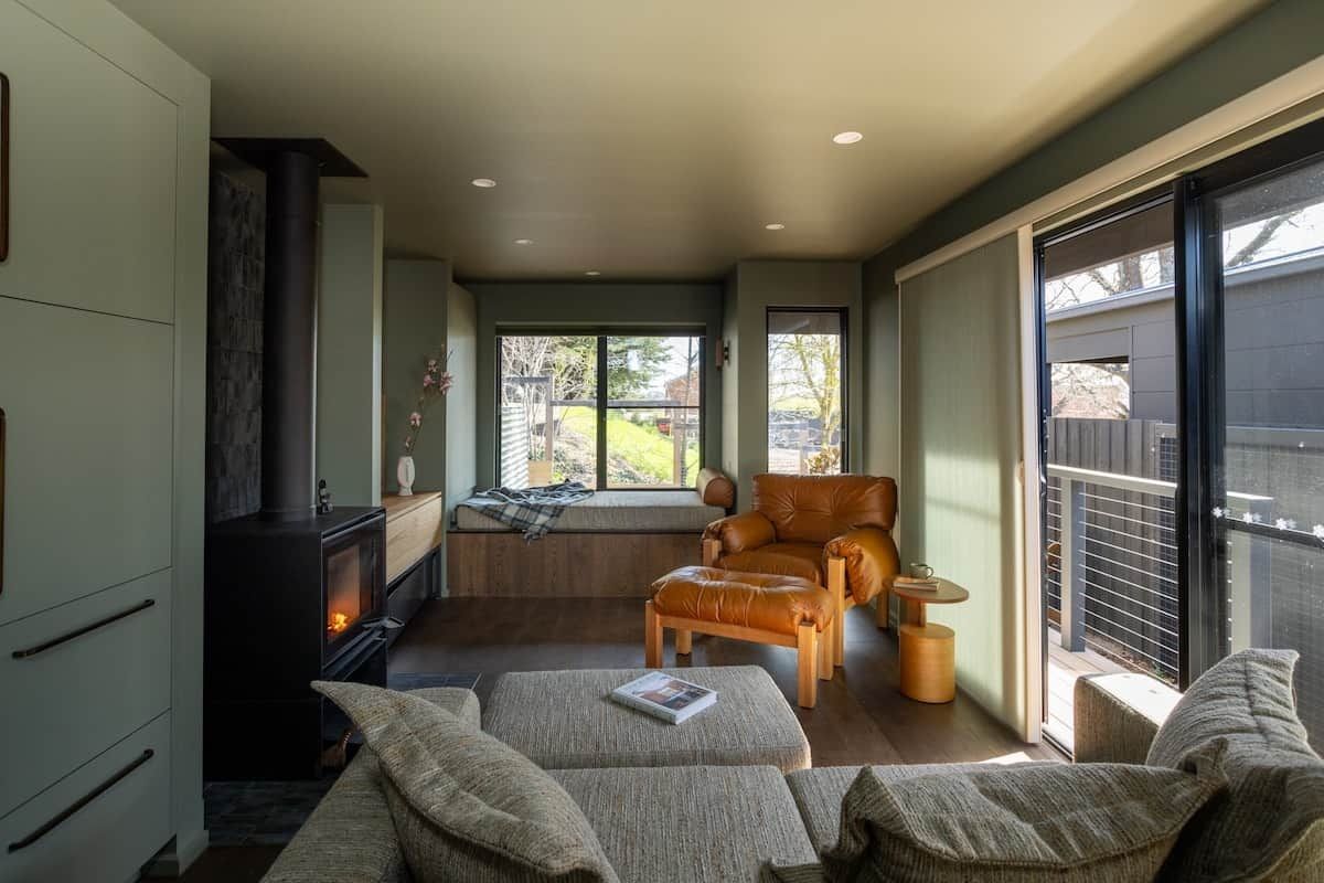 A cozy living room with a fireplace, comfortable seating, and a large window providing a view of the outdoors.