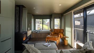 A cozy living room with a fireplace, comfortable seating, and a large window providing a view of the outdoors.