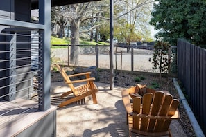 A covered outdoor seating area with two wooden Adirondack chairs and a small round table.