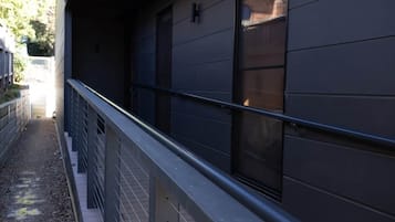 A modern building with a metal railing and a window with a dark blind.