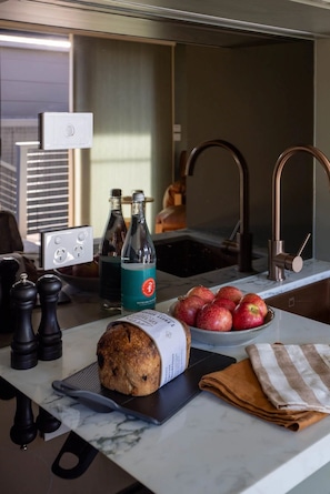 A kitchen counter with a loaf of bread, a bottle of water, and a bowl of apples.